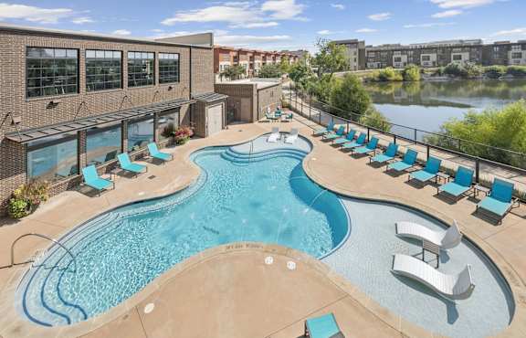 A large outdoor swimming pool with lounge chairs and a slide.