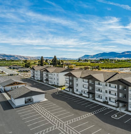 A parking lot in front of apartment buildings with a mountain range in the background.