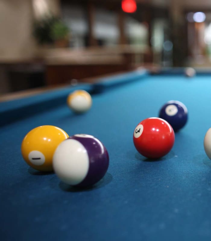 Billiard balls scattered across a blue felt pool table at Charleston at Fannin Station in Houston, Texas