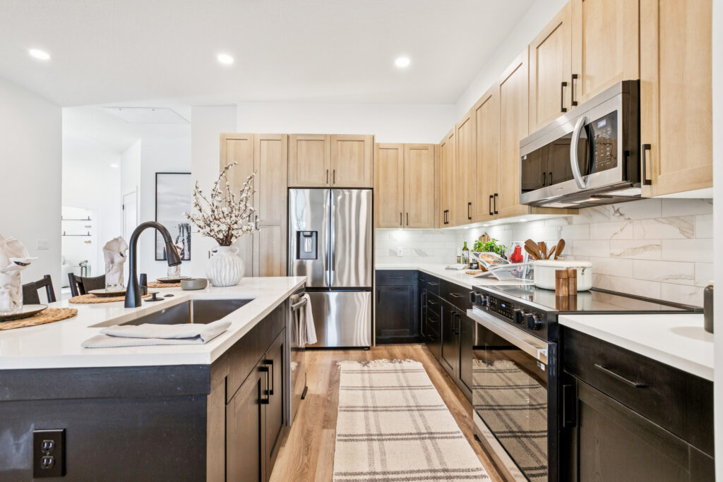 Modern kitchen with wooden cabinets, stainless steel appliances, and sleek black faucet on a white countertop.