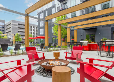 a patio with red chairs and tables and a fire pit