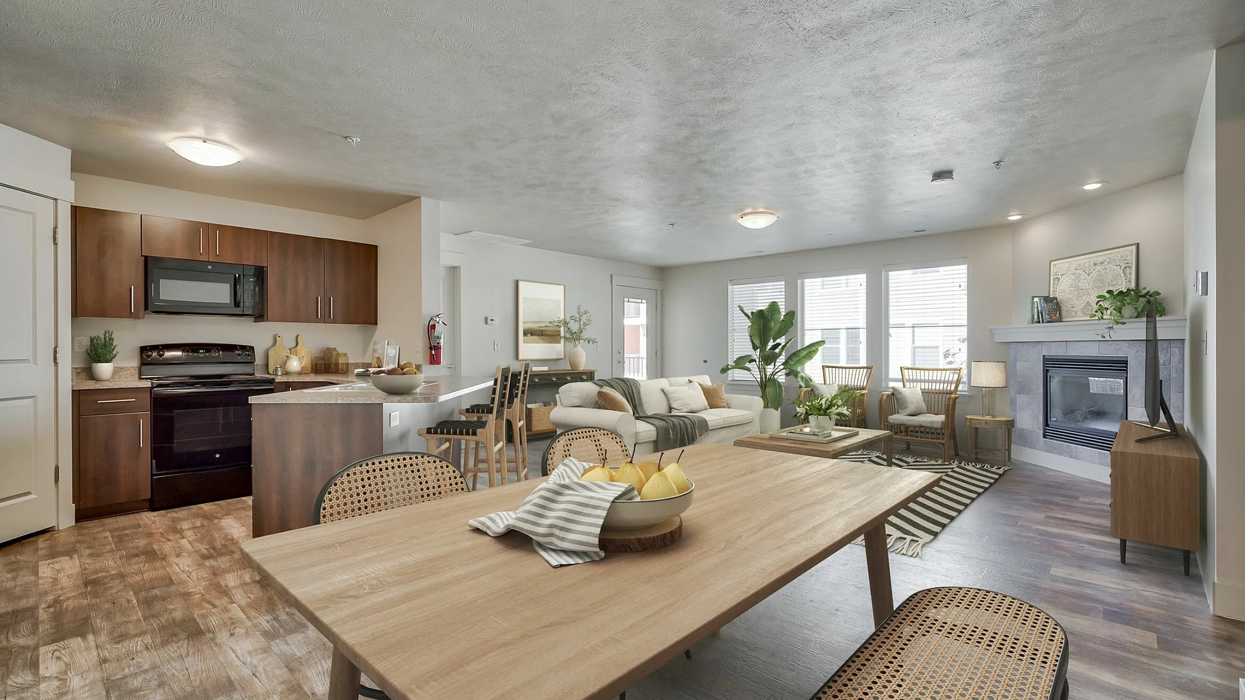 Bright, modern open-concept living area featuring a stylish kitchen, dining space, and cozy living room with a fireplace, all accentuated by abundant natural light.