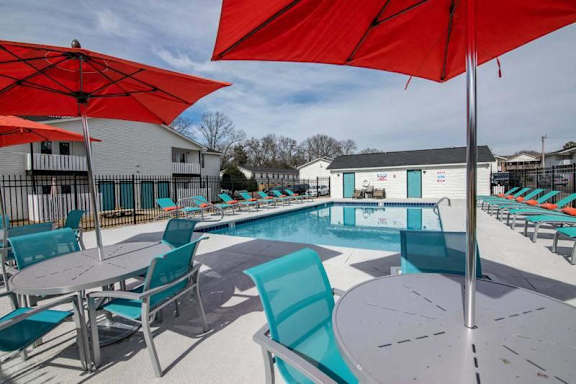 a swimming pool with tables and chairs and umbrellas