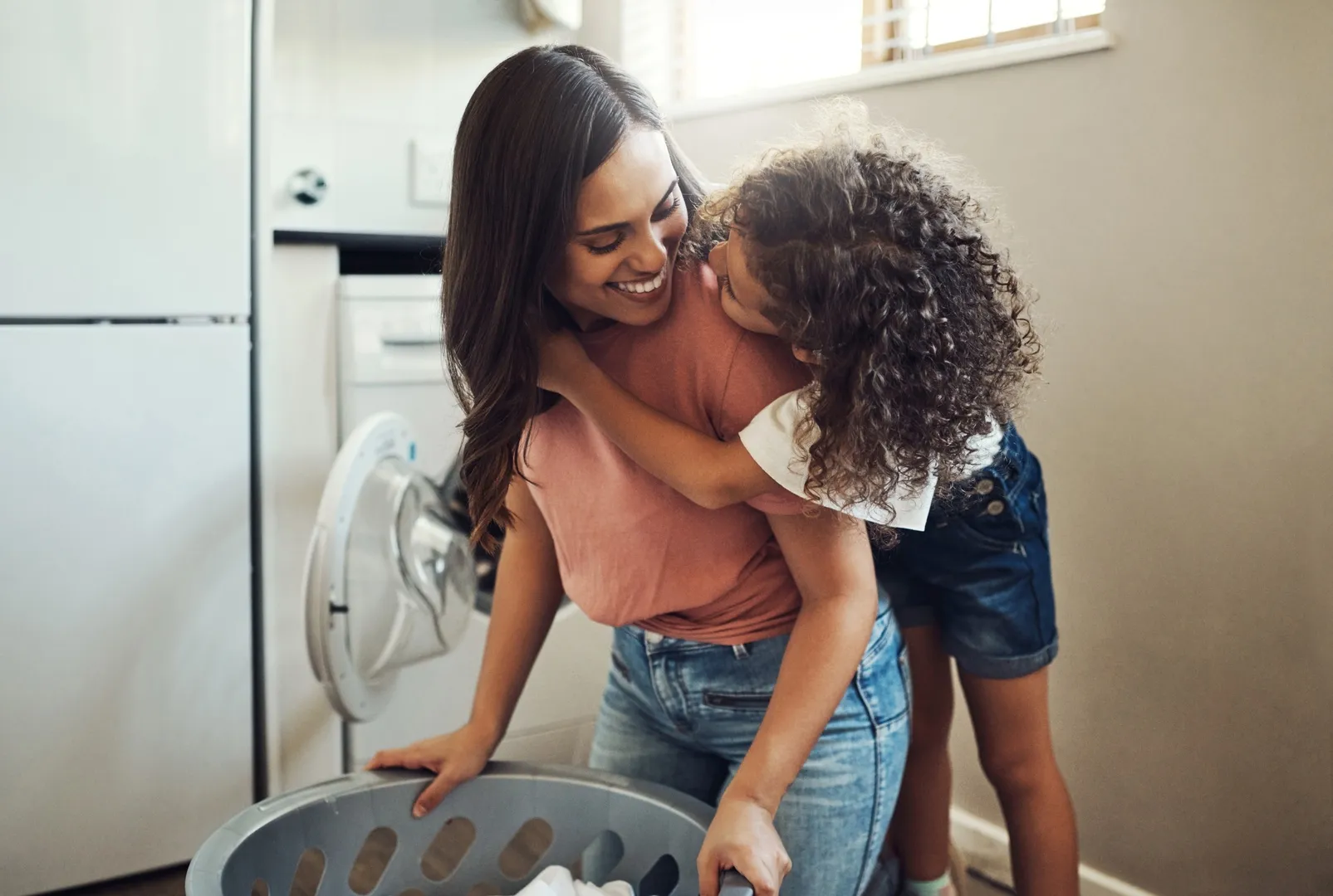 Woman doing laundry while a child hugs her