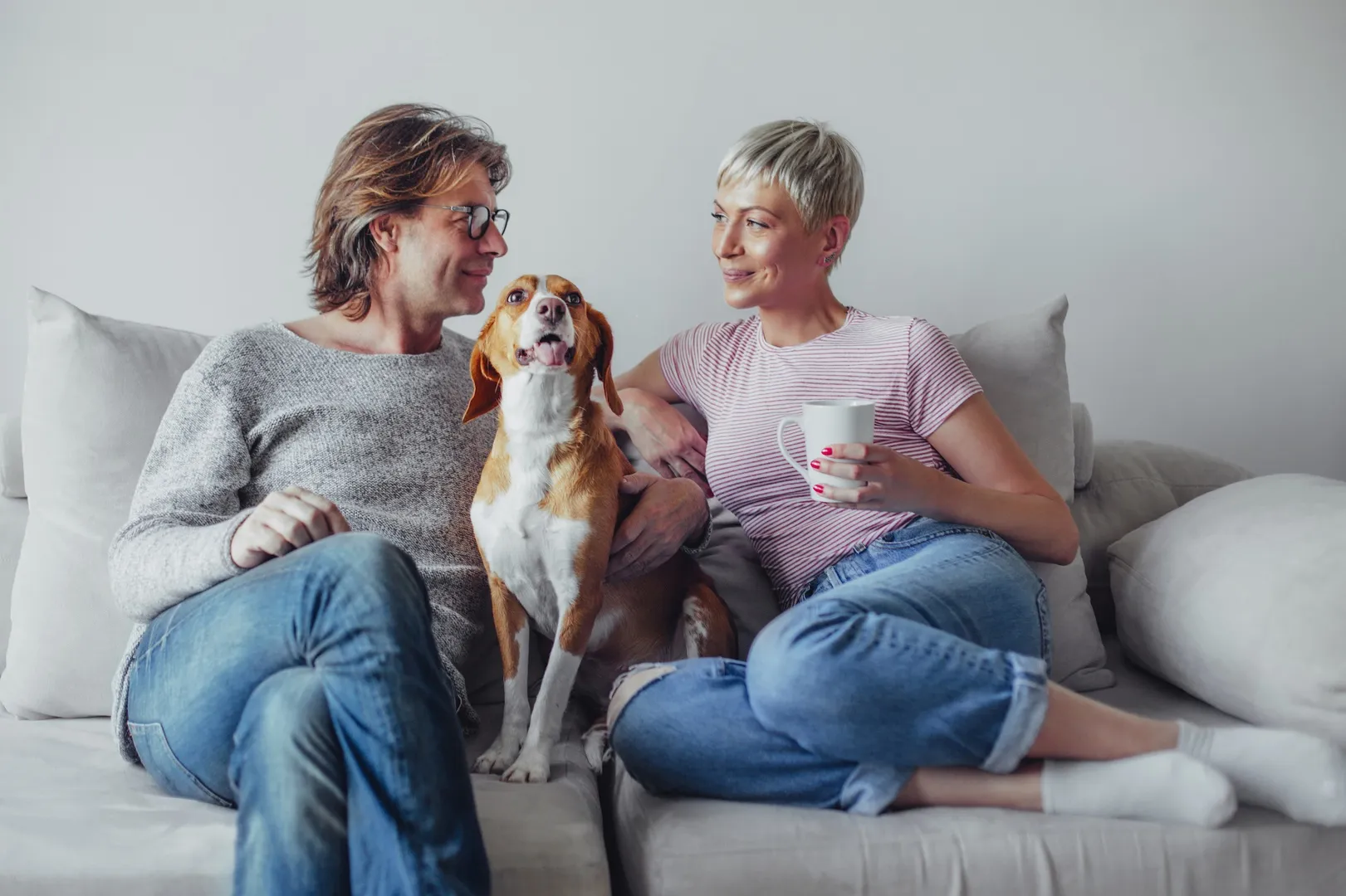 Two people relaxing on a sofa with their dog
