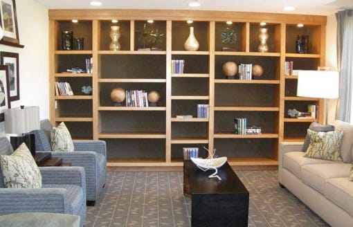 Novato CA Pet-Friendly Apartments - Millworks - Social Room with Couch, Armchairs, Coffee Table, Bookshelves, and Lamp Lighting.