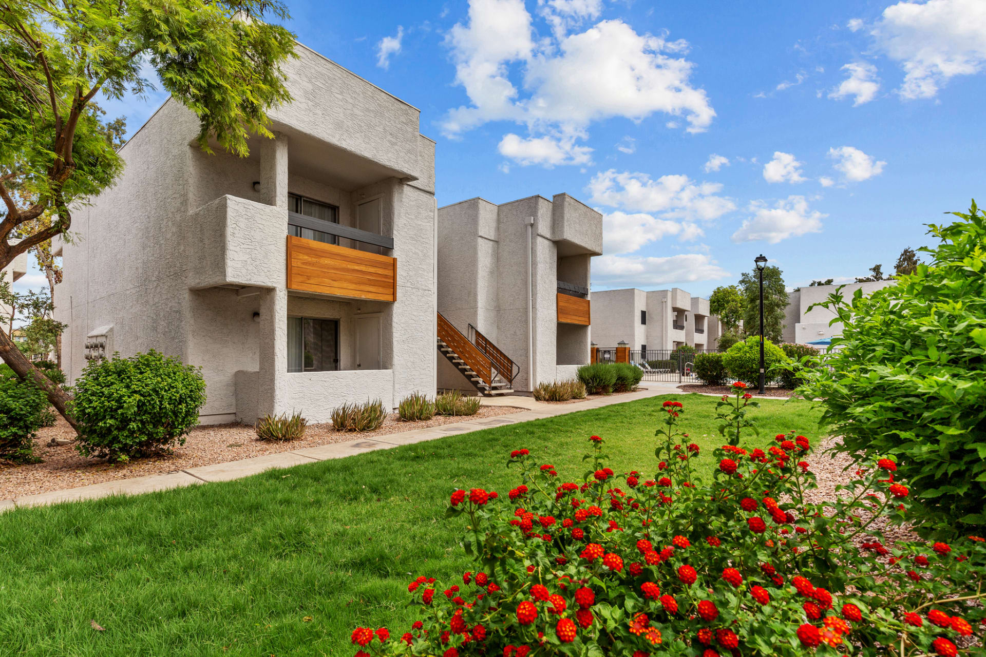 the exterior of an apartment complex with flowers and bushes at The Tides on 27th