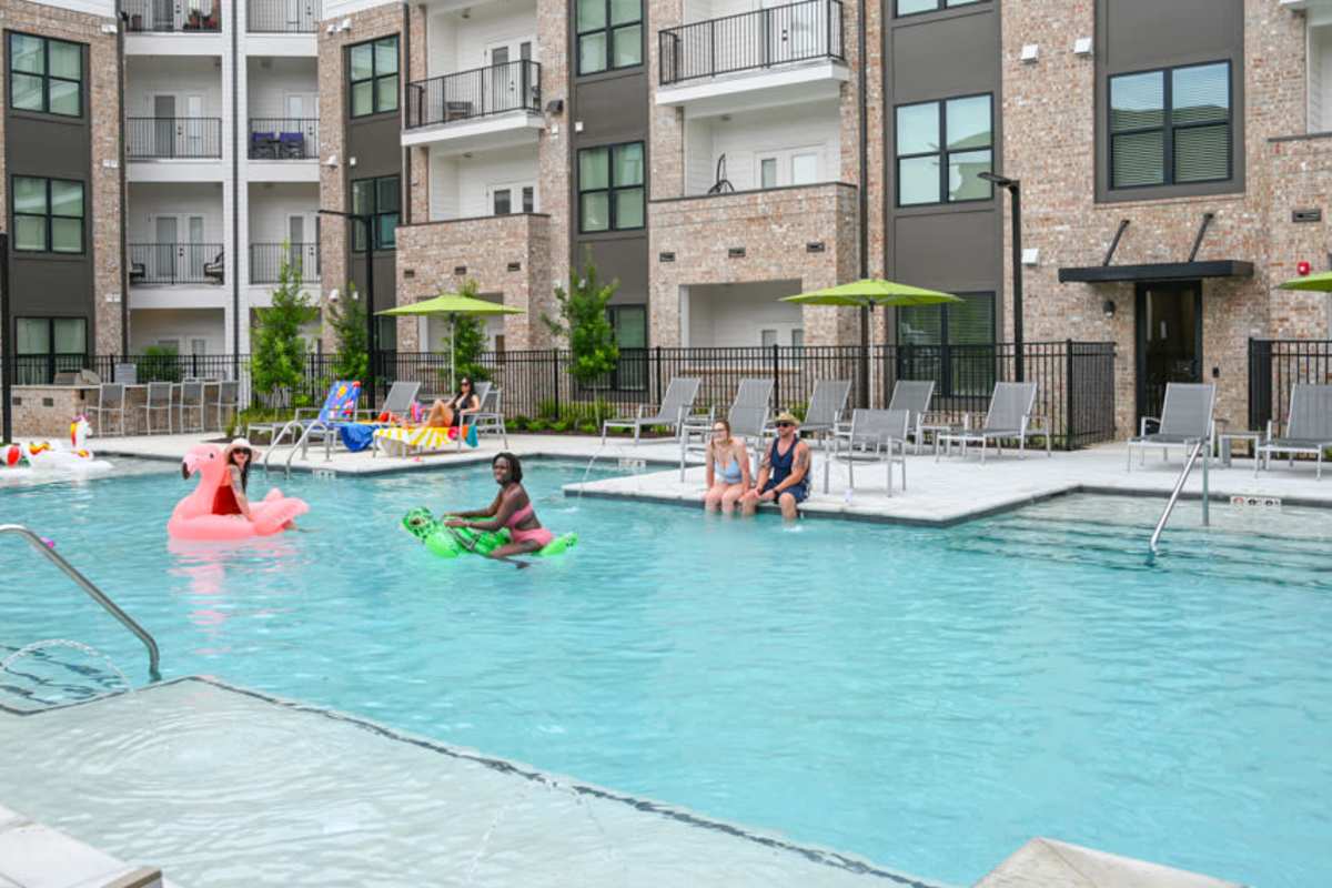 residents enjoying a swimming pool with tanning shelf at The Heights at Waterpointe in Flowood, Mississippi