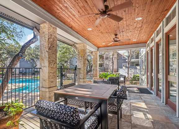 A patio with a table and chairs overlooking a pool.