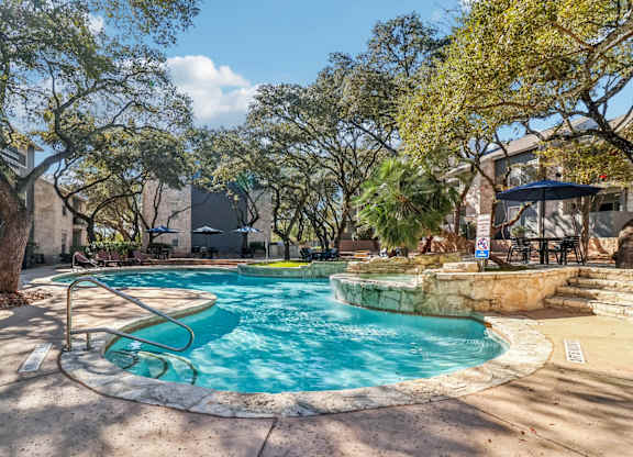 A swimming pool surrounded by trees and a patio area.