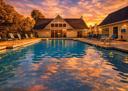 A pool with a house in the background during sunset.