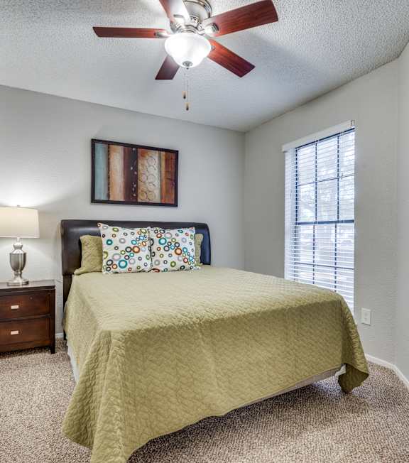 A bedroom with a bed, a dresser, and a ceiling fan.