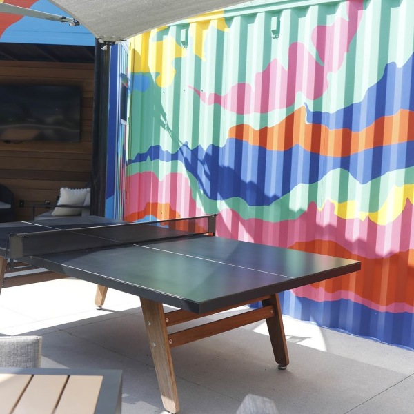 a ping pong table outside next to a colorful wall