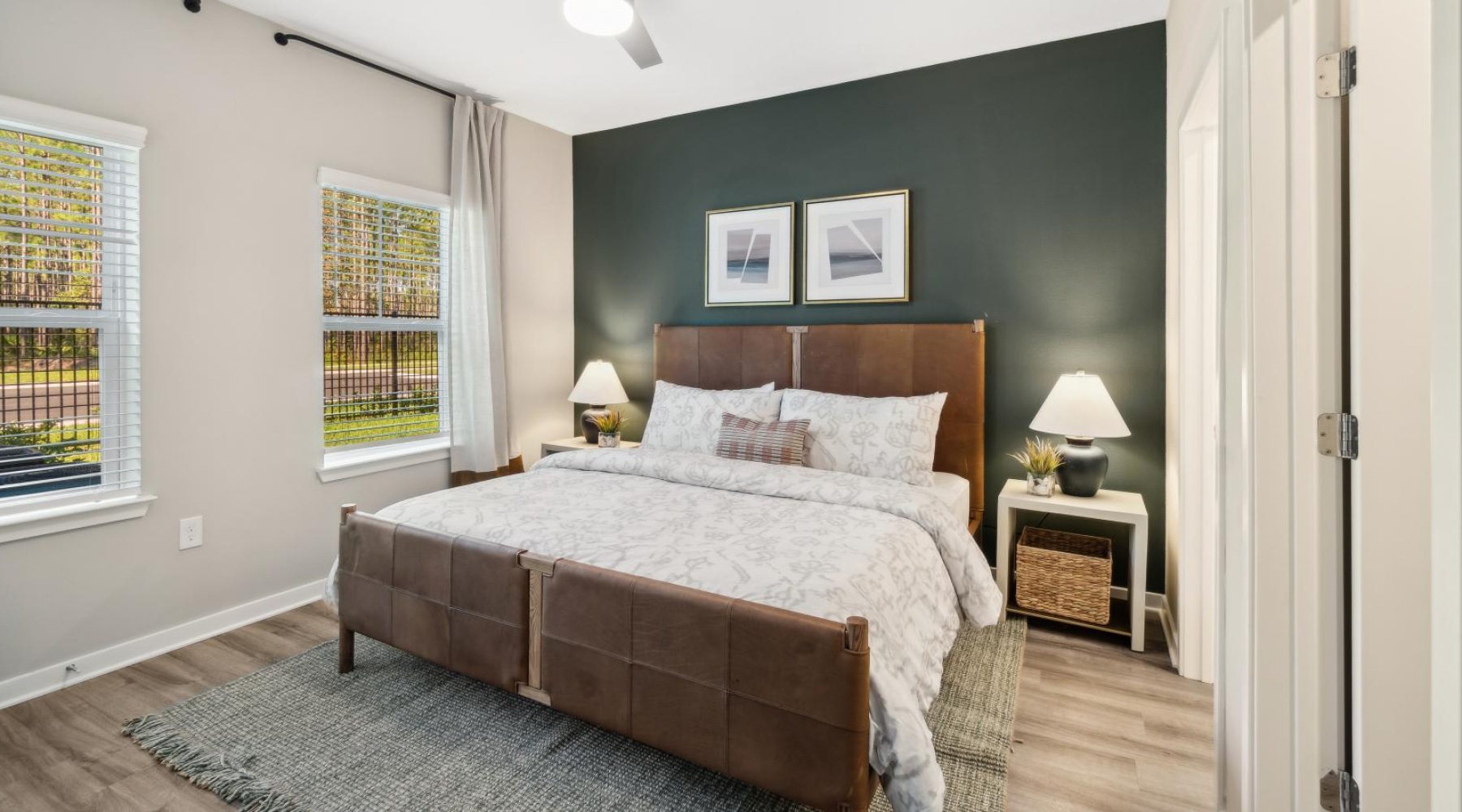 Luxury Apartments in St. Johns, FL, with In-Unit Washer and Dryer - Ascend Durbin Park - Bedroom with Hardwood-Style Flooring, Bed, Two-Toned Walls, Ceiling Fan, Nightstands, Lamps, and Large Windows.