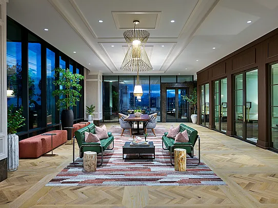 Luxurious modern lounge area featuring elegant seating, chic lighting, and large glass windows with a stunning city view.