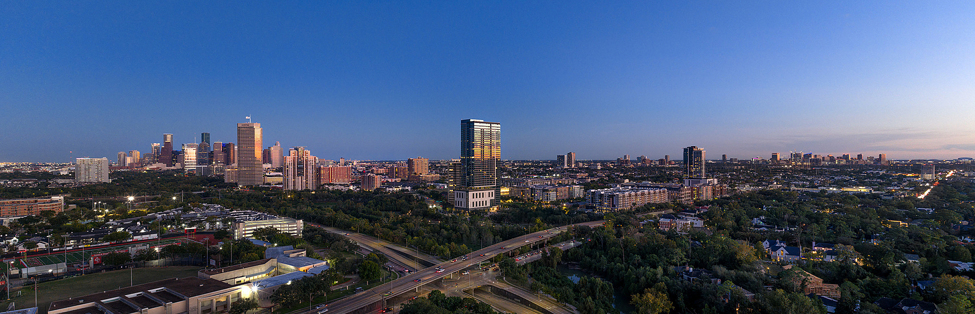 Breathtaking cityscape view showcasing a vibrant skyline at dusk, with lush greenery and a serene sky, offering an ideal urban living experience.
