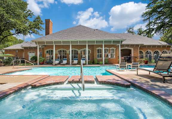 A pool in front of a house with a porch.