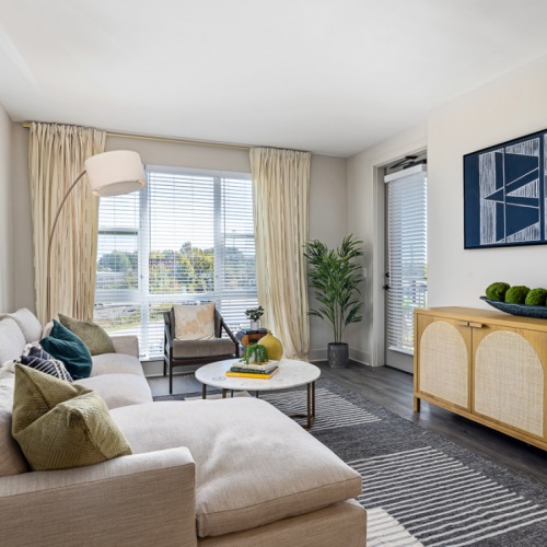 Spacious and well lit living room with wood floors and an open floor plan with access to the kitchen