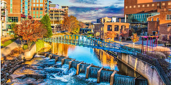 A bridge over a river with water flowing over the weir.