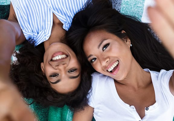 a mother and daughter laying on the ground with their arms around each other