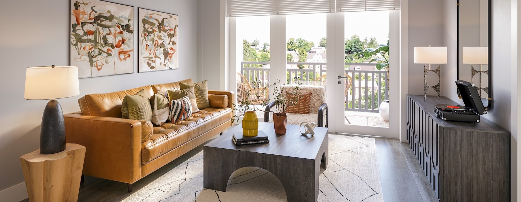 An interior view of a living room with a couch and a patio door, with views of a balcony at Solstice at Eastland Yards apartments in Charlotte, NC.