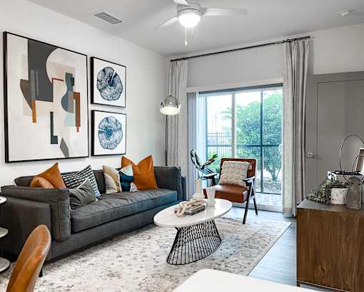 A living room with a grey couch, a coffee table, and a painting on the wall.