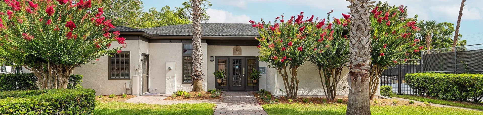 Charming and inviting entrance surrounded by lush greenery and vibrant flowers, offering a welcoming atmosphere.
