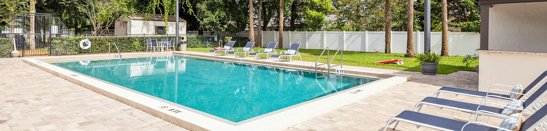 Inviting outdoor pool area featuring crystal-clear water, surrounded by comfortable lounge chairs and lush greenery for a relaxing retreat.