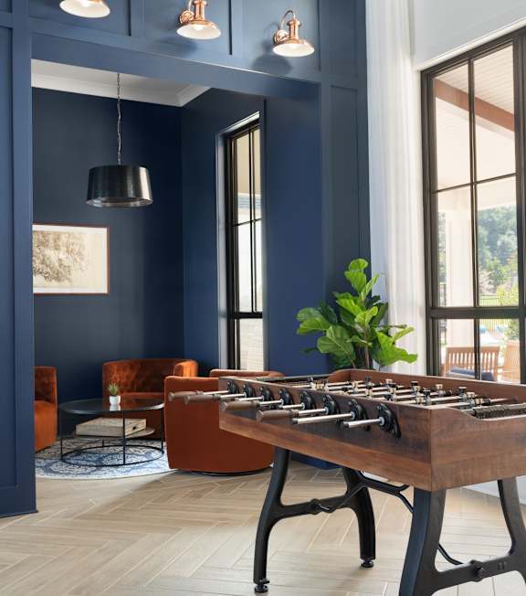 A foosball table sits in the middle of a room with blue walls and a large window.