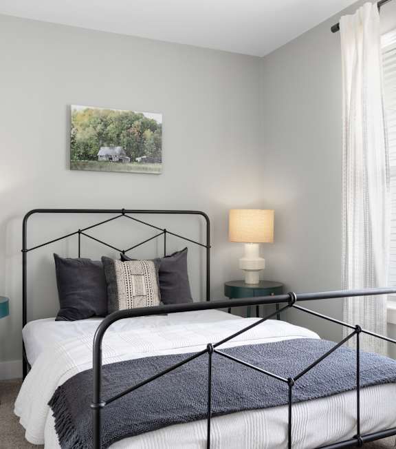 A bedroom with a large bed and two lamps.