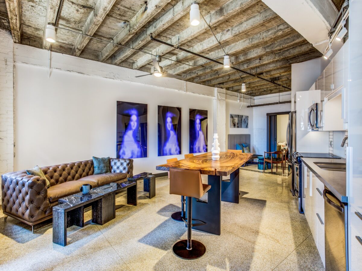 Living, dining, and kitchen combined space with pendant lighting, fan, hard flooring.