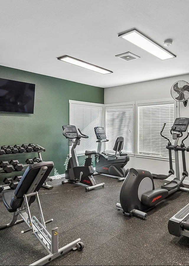 Modern fitness center with state-of-the-art treadmills, stationary bikes, and a versatile weight rack in a well-lit, inviting space.