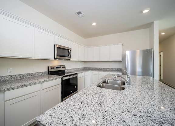 a kitchen with granite counter tops and a stainless steel refrigerator