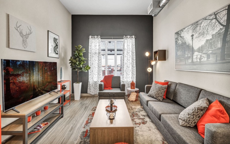 Spacious well lit living room with wood floors and large windows 