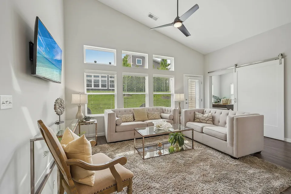 Elegant living room with plush sofas, modern decor, and abundant natural light streaming through large windows overlooking a lush green lawn.