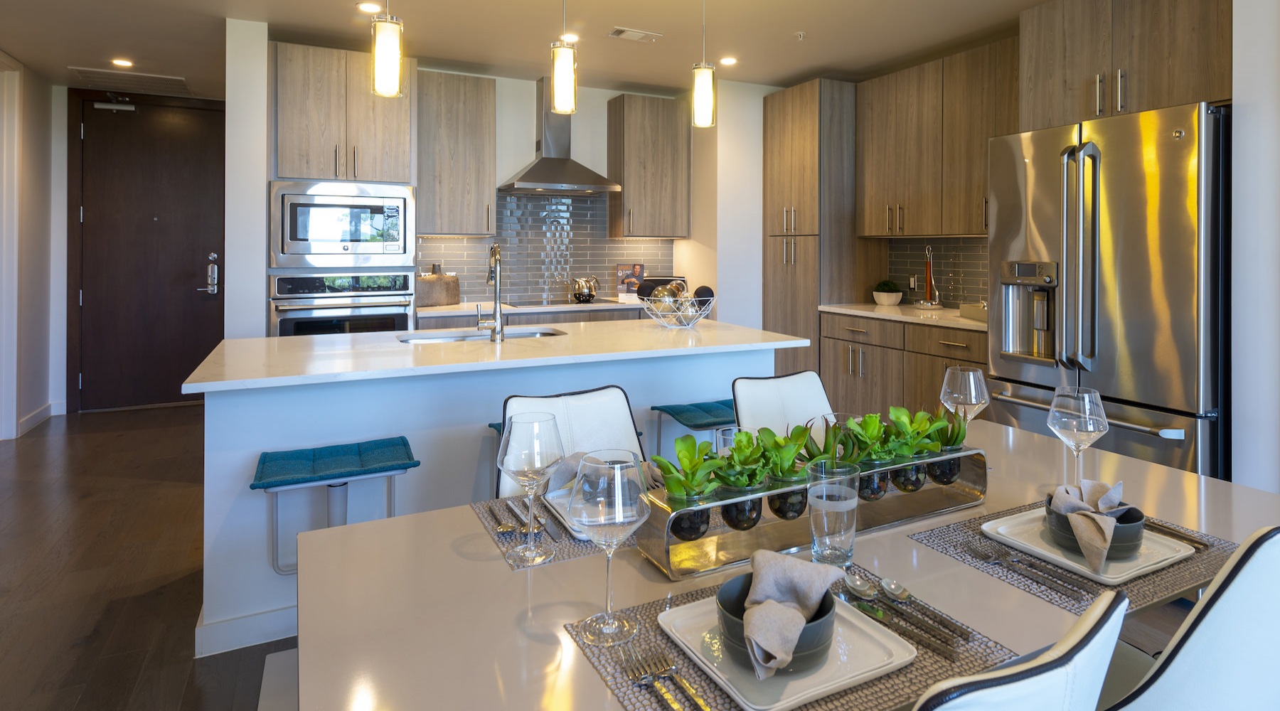 Spacious kitchen that is well lit with wood floors and stainless steel appliances with complete access to the living room 