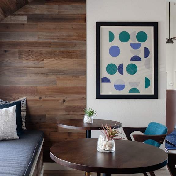 A modern living room with a wooden wall and a blue couch.