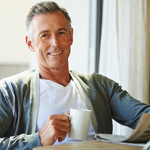 Gentleman reading newspaper while drinking coffee
