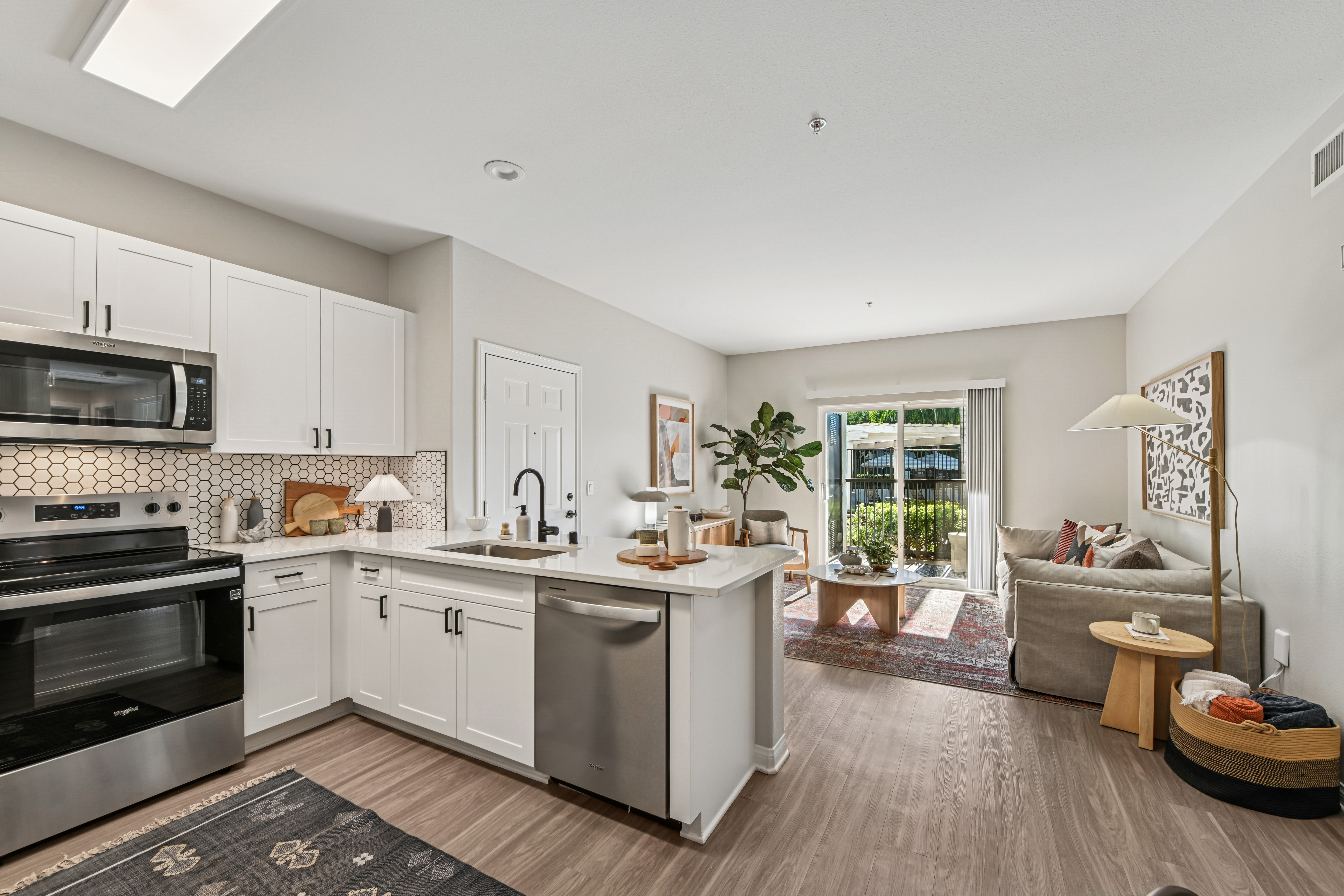 Kitchen with white cabinets and stainless steel appliances with a view of the living room
