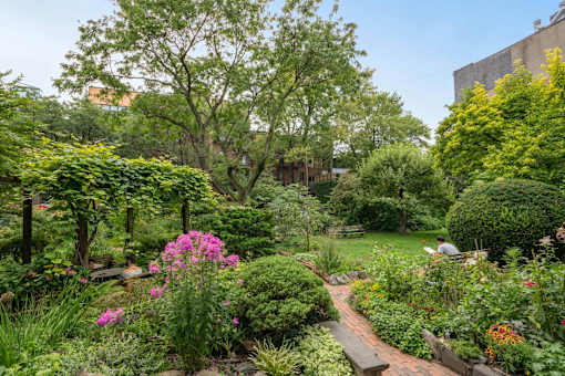 A garden with a brick pathway and a variety of plants and flowers.