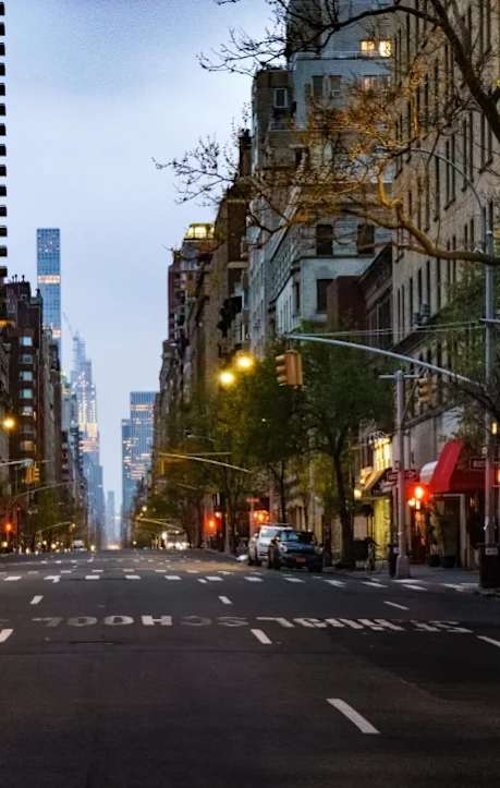 A city street with a car driving down it and buildings on either side.