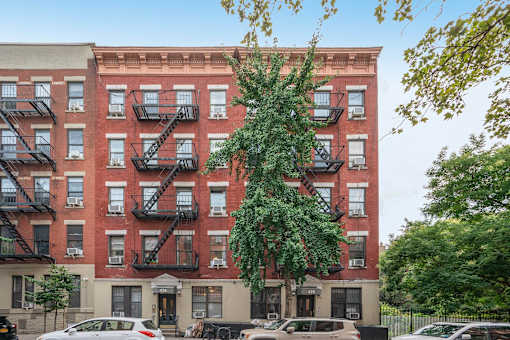 A red brick building with black fire escapes on the side.
