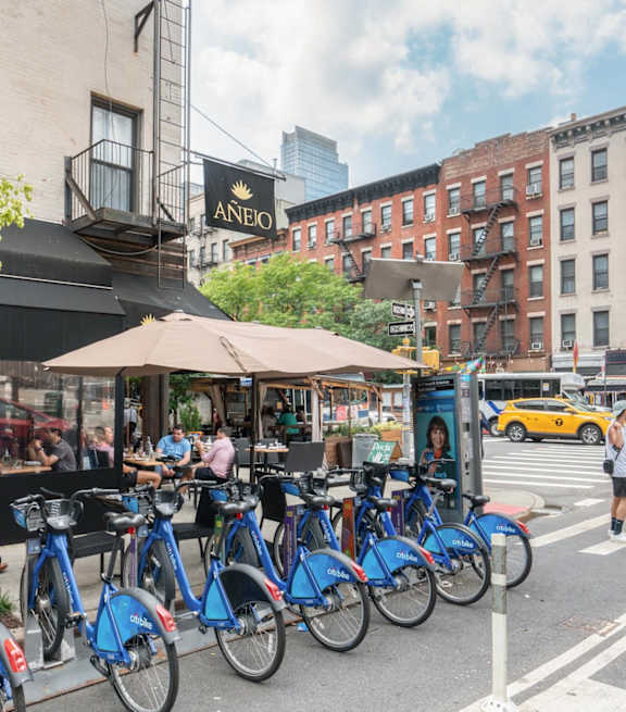 A row of blue bikes are parked on the side of a street.
