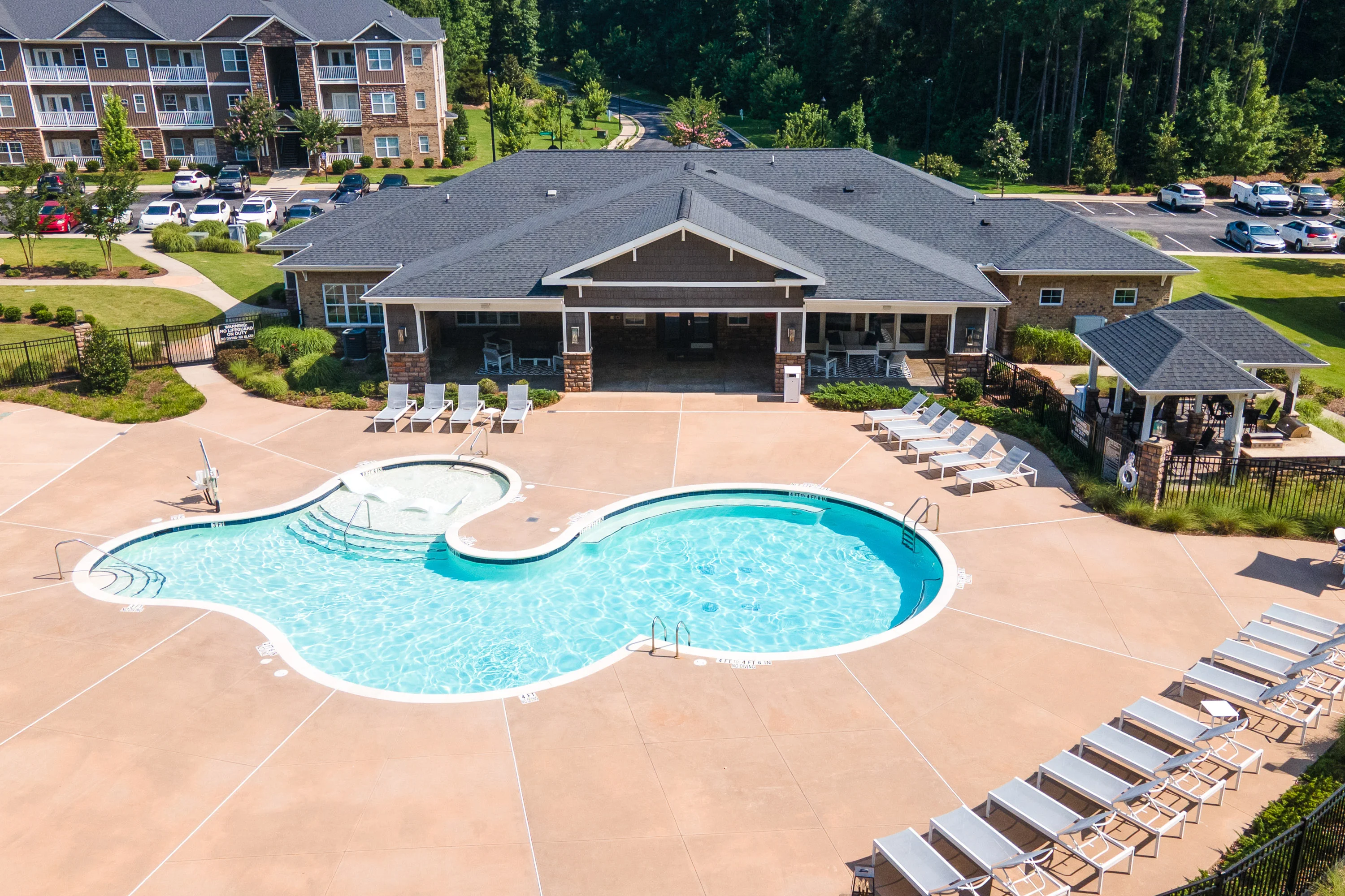 Aerial view of an apartment pool area featuring a large, inviting pool and a poolside lounge with seating.