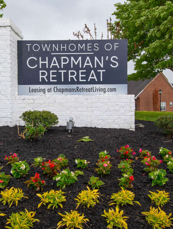 A sign for the Townhomes of Chapman's Retreat is surrounded by flowers.