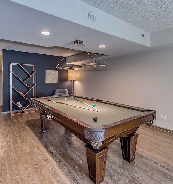 A pool table in a room with wooden flooring and a white ceiling.