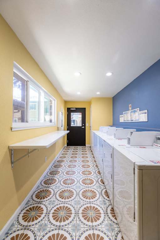 a laundry room with blue and yellow walls and a tile floor