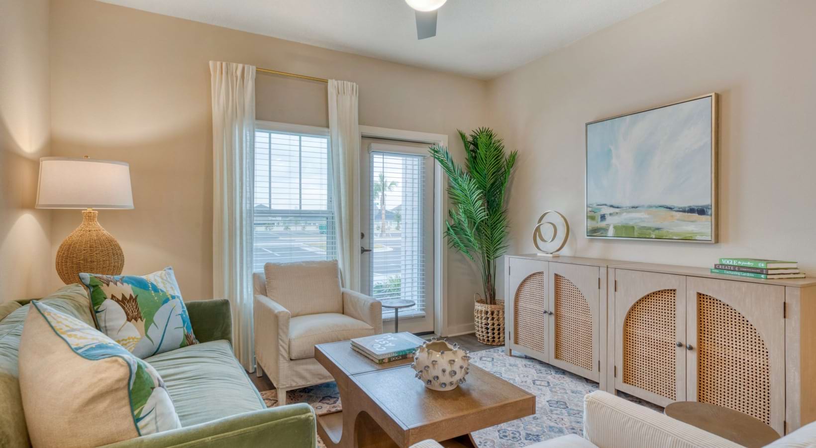 Palm Coast, FL pet-Friendly Apartments - Marbella Palm Coast - A Living Room with a Wooden Coffee Table and Floor-to-Ceiling Windows.