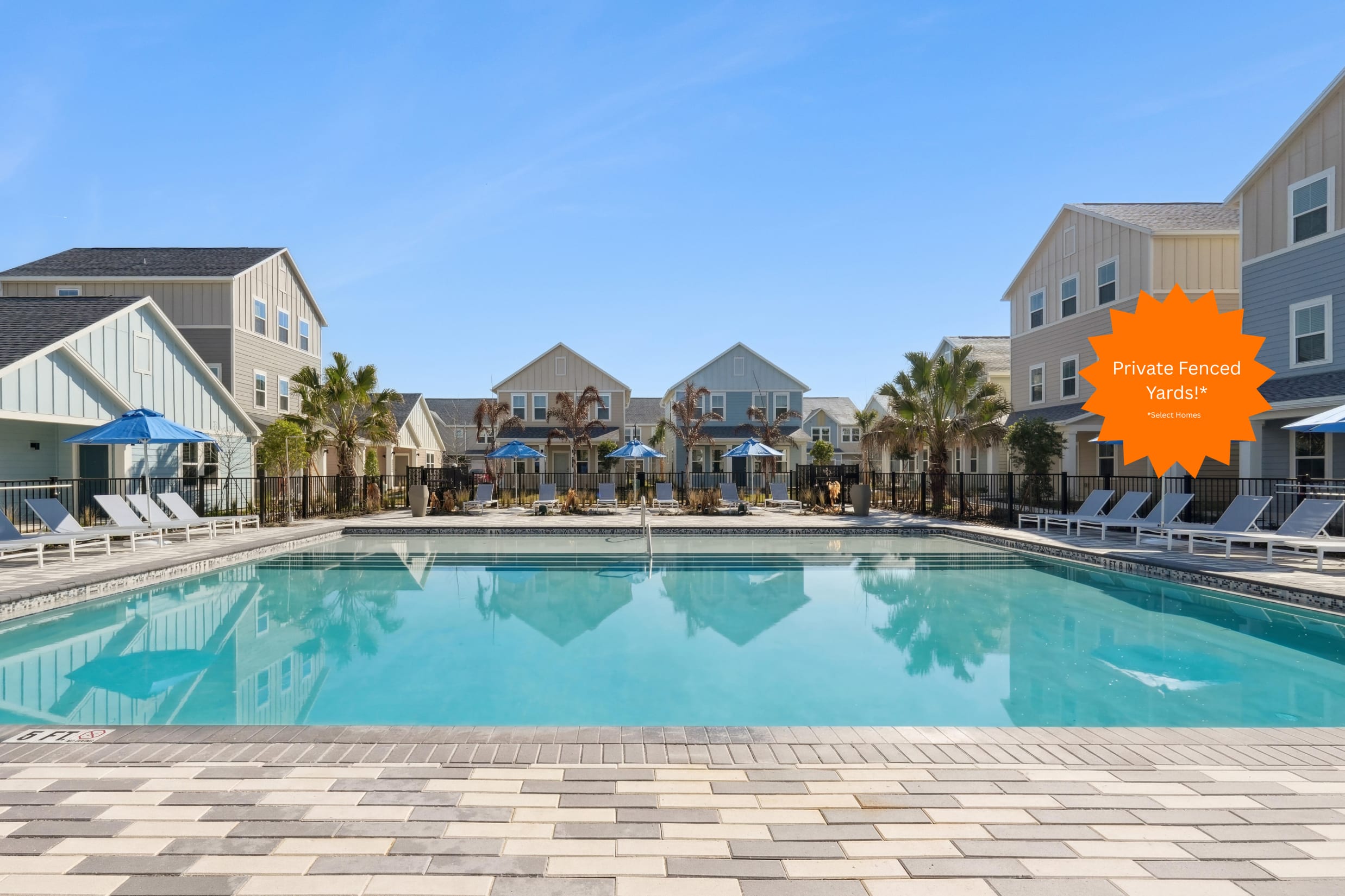 Resort-style pool with lounge chairs and townhomes at Hamlet at Avalon Park in Wesley Chapel, Florida