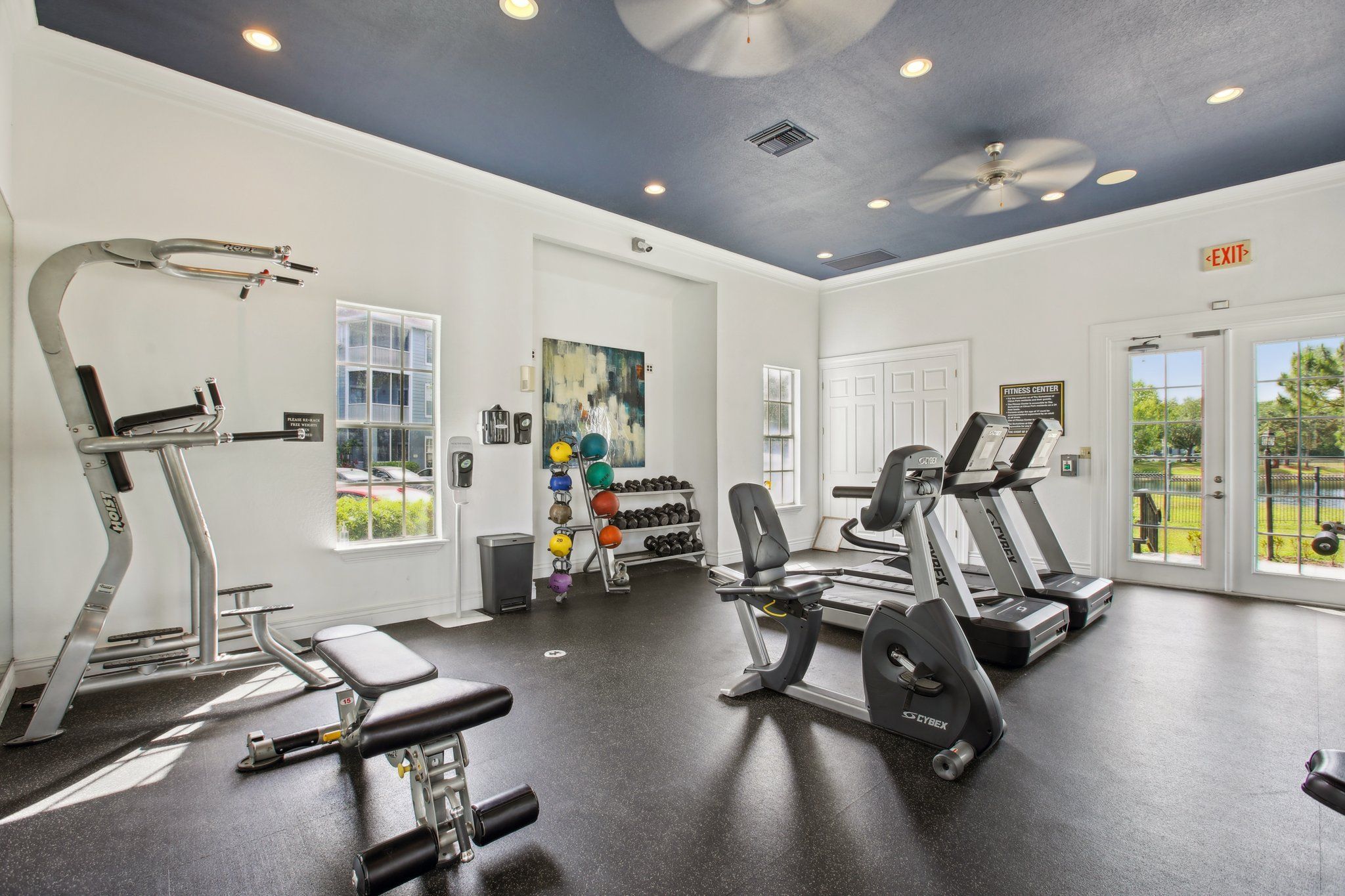 A bright and spacious gym featuring various exercise machines and free weights.